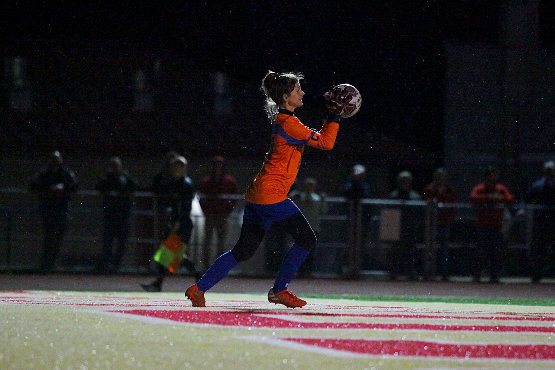 A football player is catching a ball on a field in the rain.