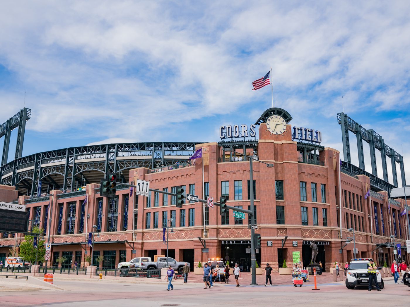 Daytime view of a brick baseball stadium with an American flag and cloudy sky