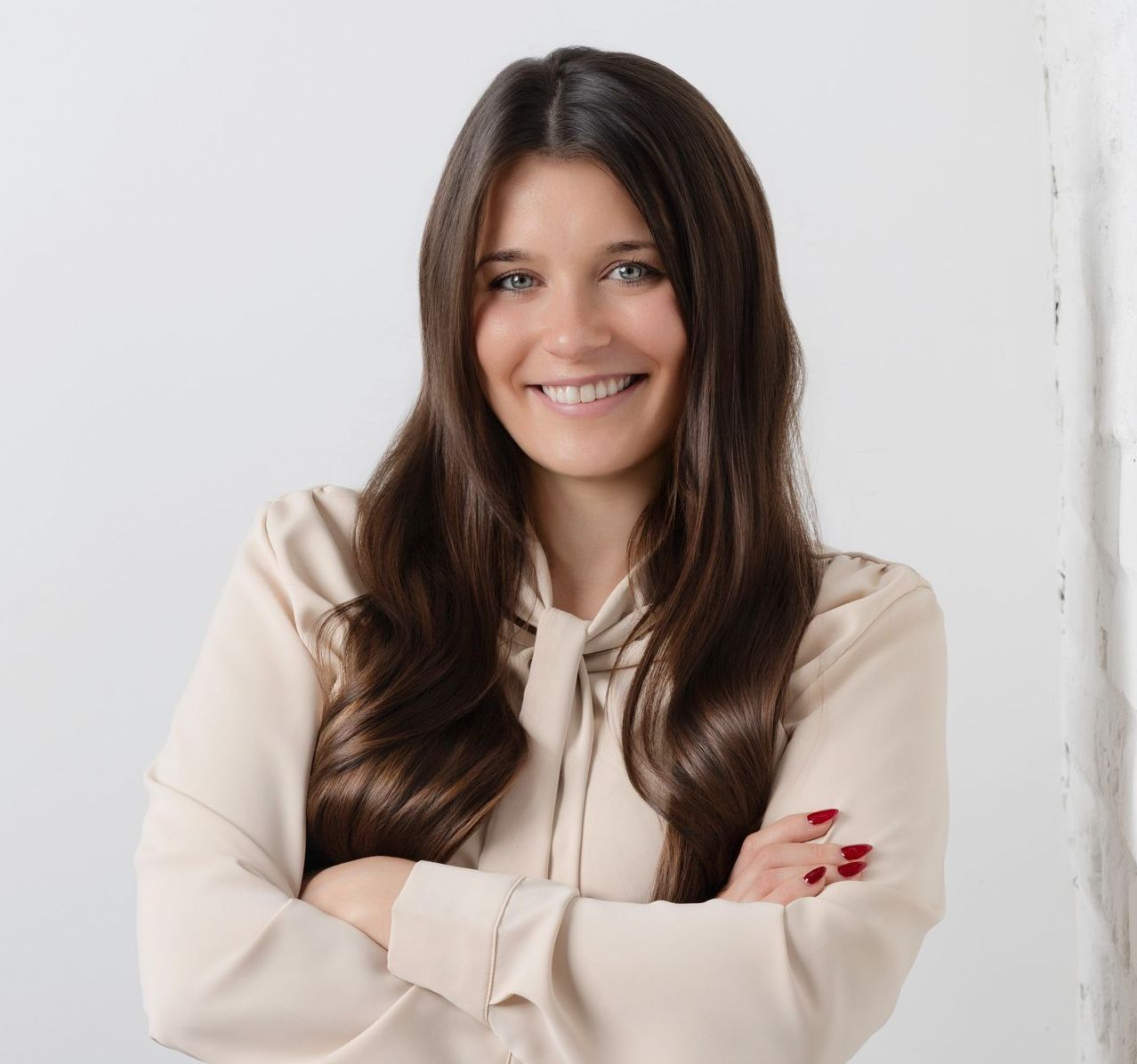 A woman is sitting on a chair in front of a brick wall. Ashley Kersey Realtor