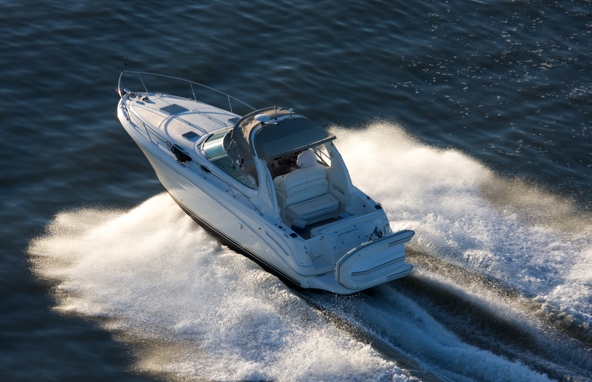 White motorboat speeding across water, creating white wake.