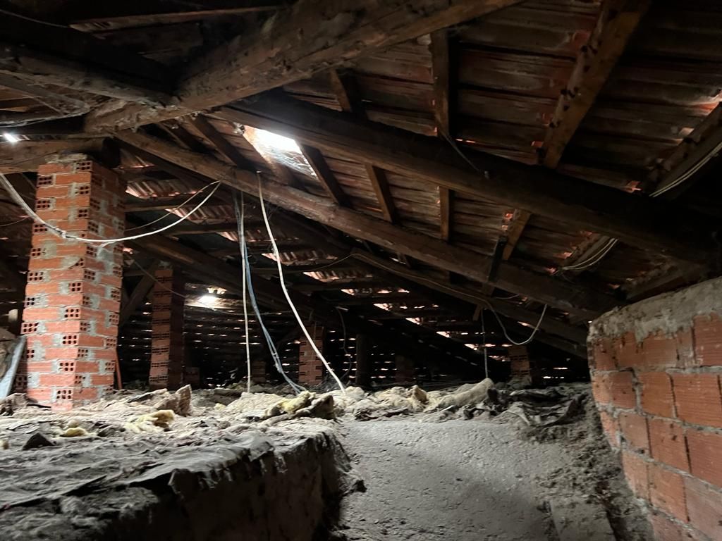 Una soffitta buia con muro di mattoni e travi in ​​legno