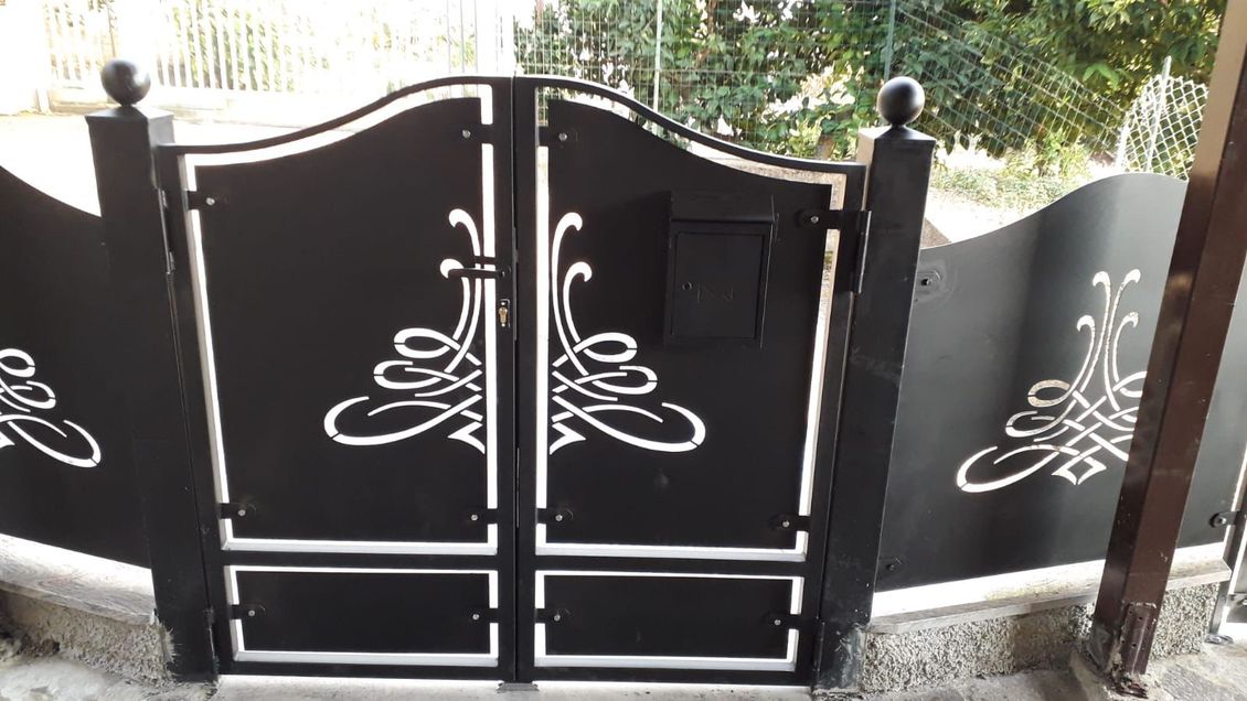 Cancello in metallo nero con volute decorative bianche e cassetta della posta.