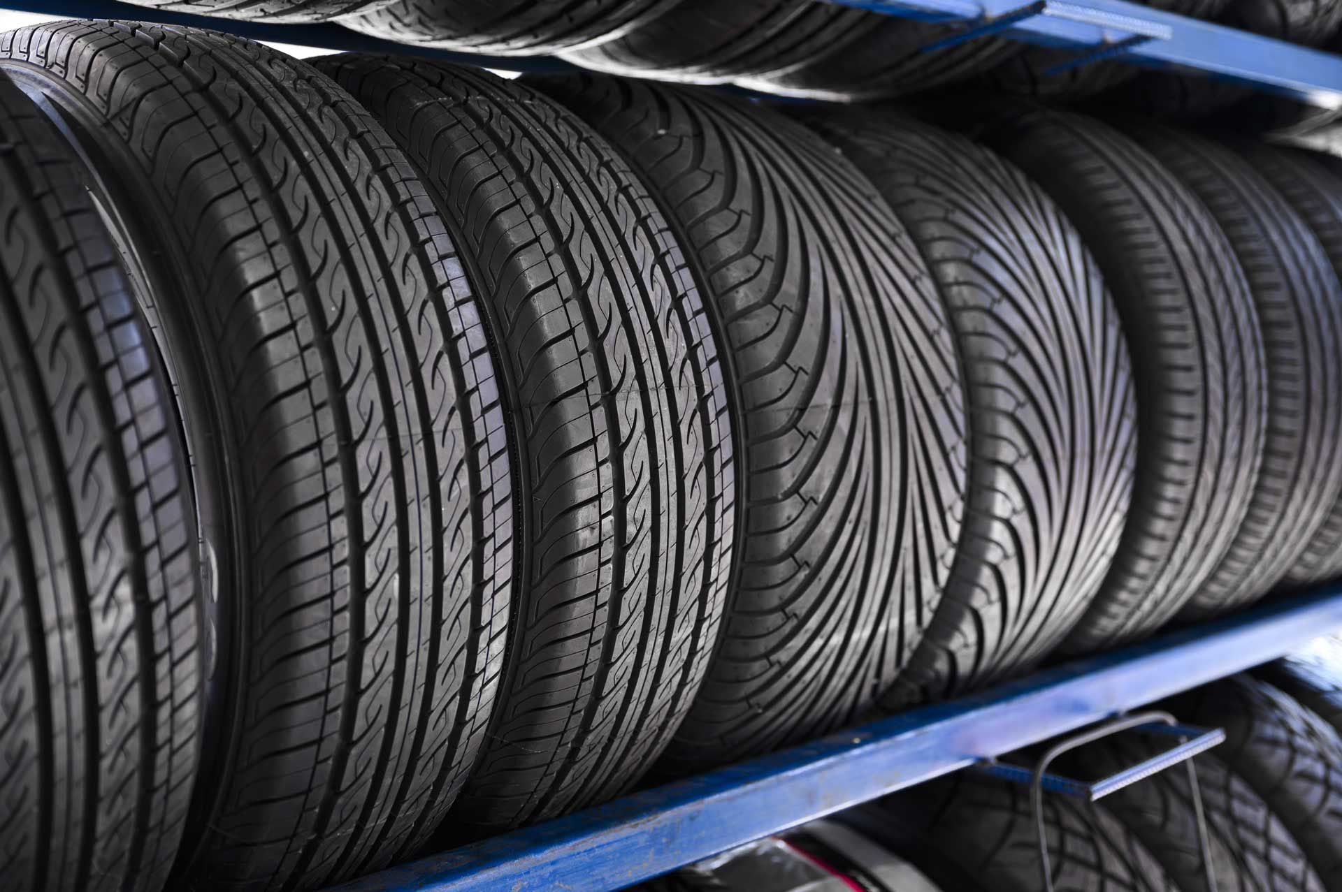 Rows of black car tires on a blue metal rack in a tire shop.