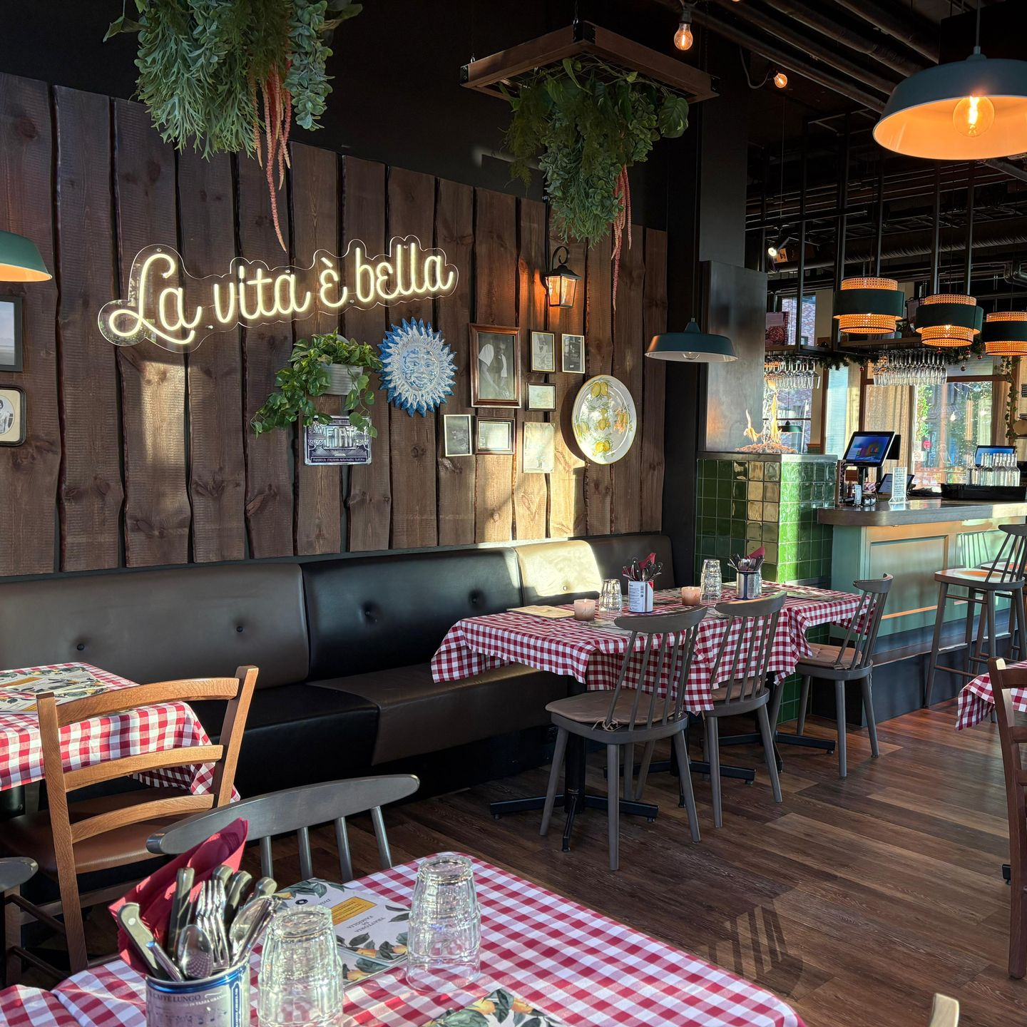Pizza with toppings, pasta, and a drink on a checkered table.