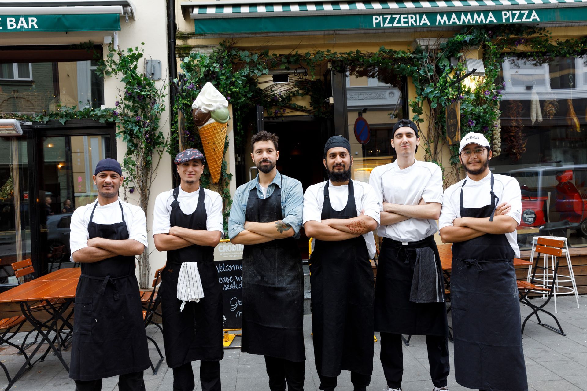 Six chefs in aprons standing in front of