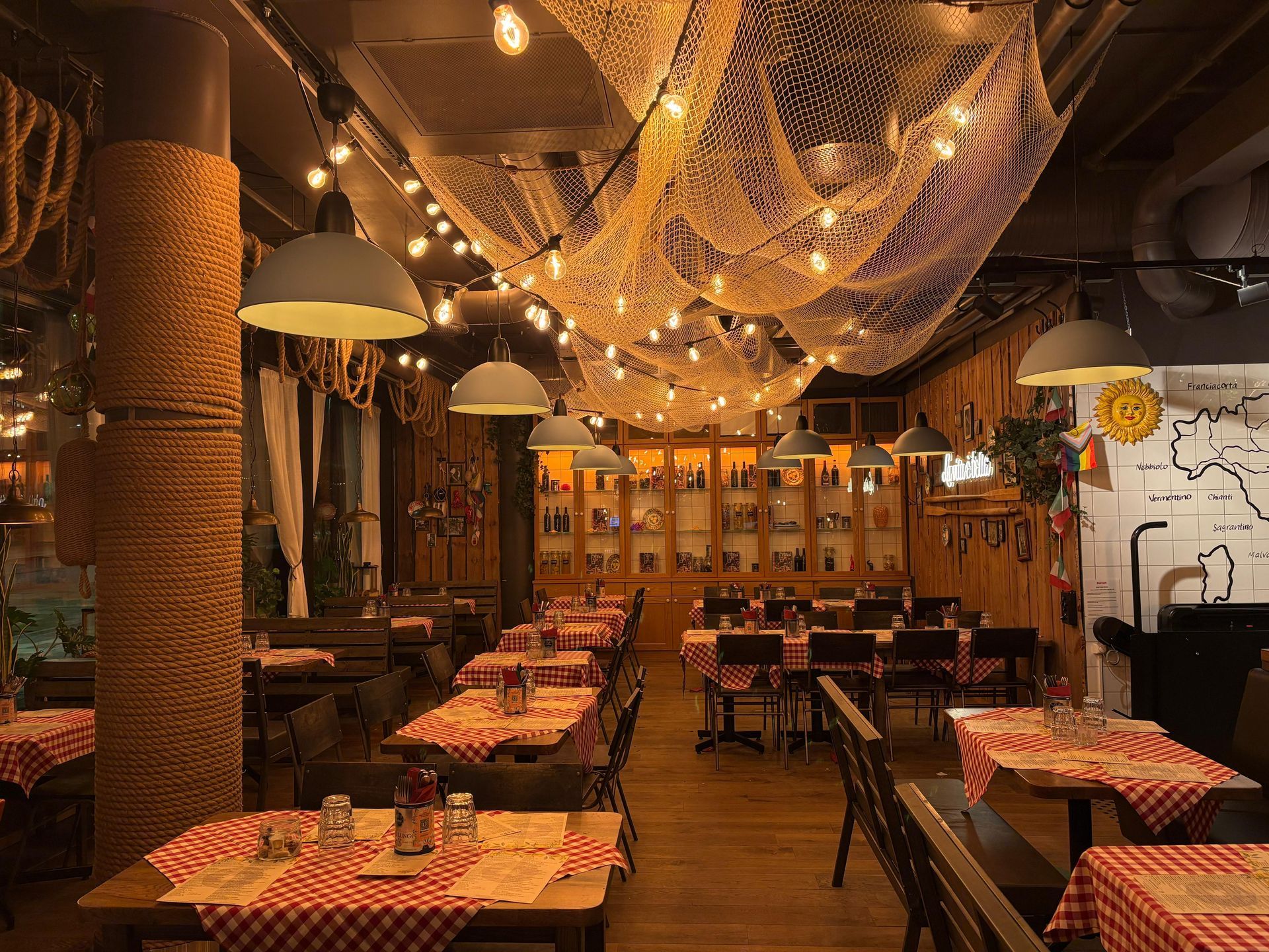 Restaurant interior with tables set for dining, nautical decor, and soft lighting.