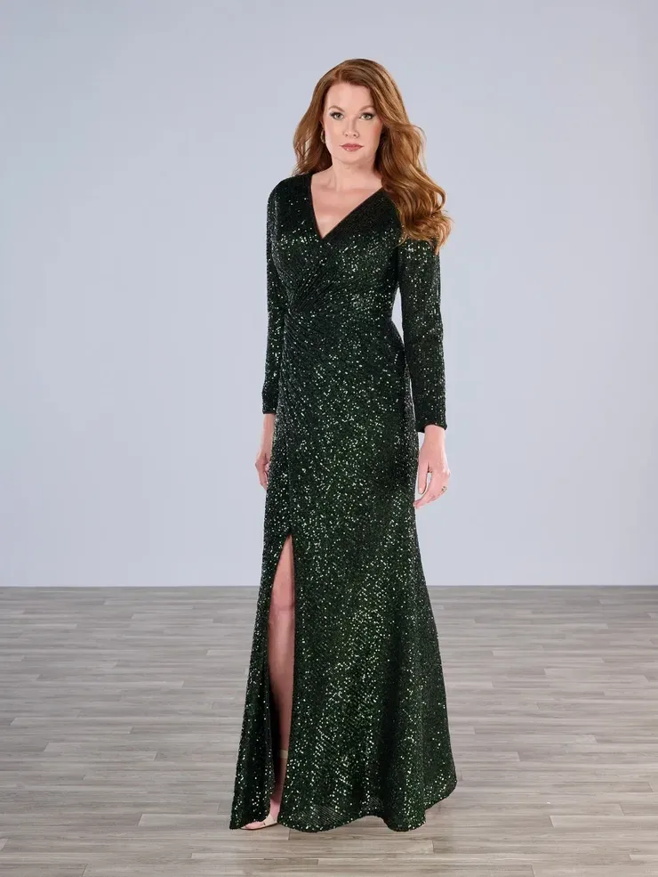 A woman in a green sequined dress is standing on a wooden floor.