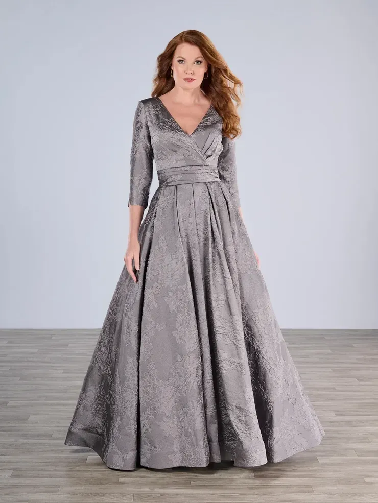 A woman in a long gray dress is standing on a wooden floor.