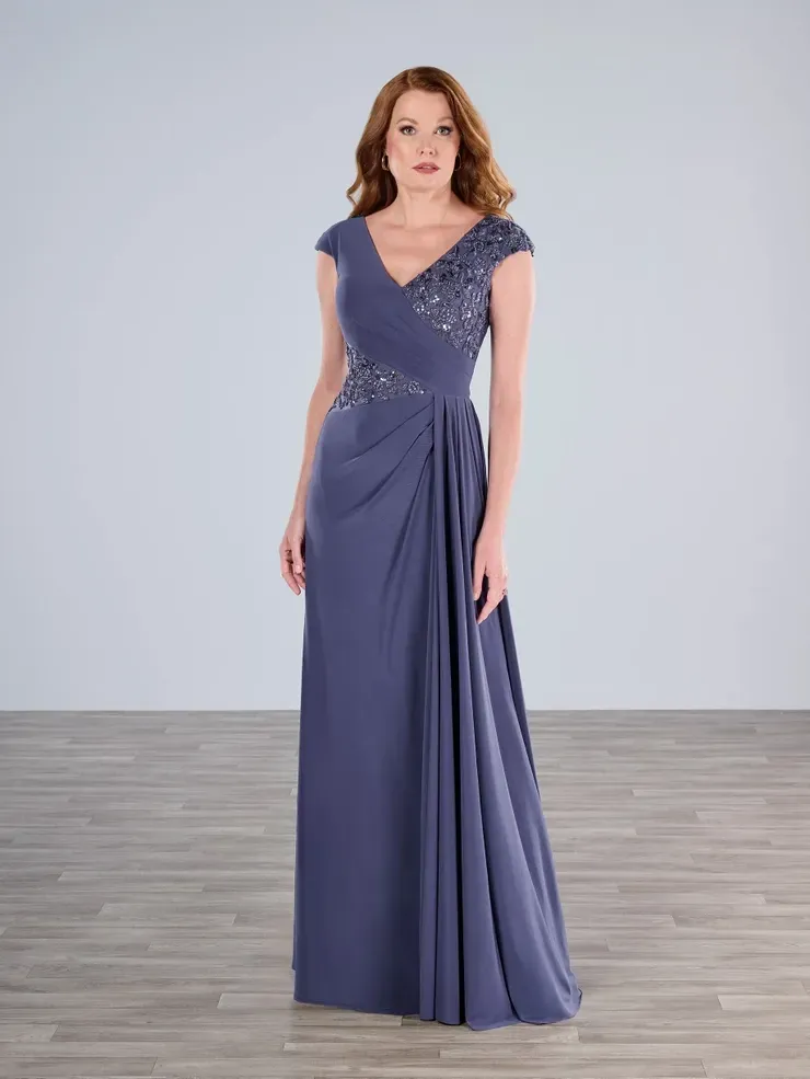 A woman in a long purple dress is standing on a wooden floor.
