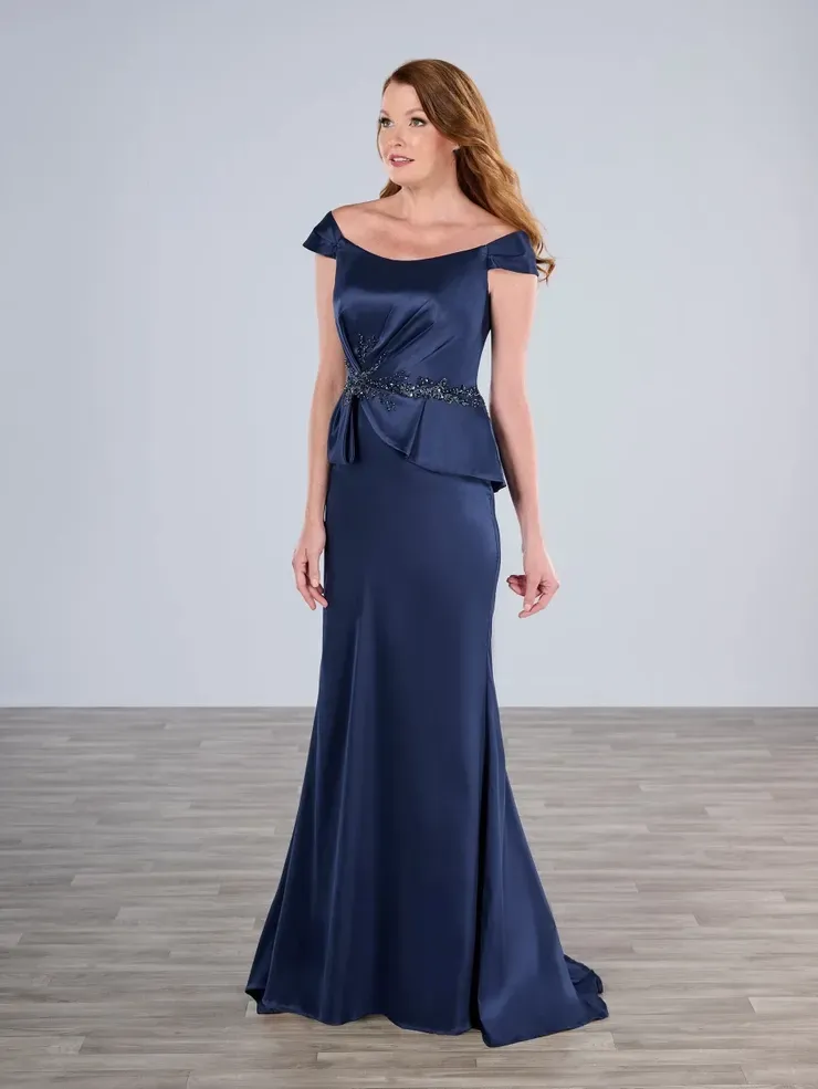 A woman in a long blue dress is standing on a wooden floor.