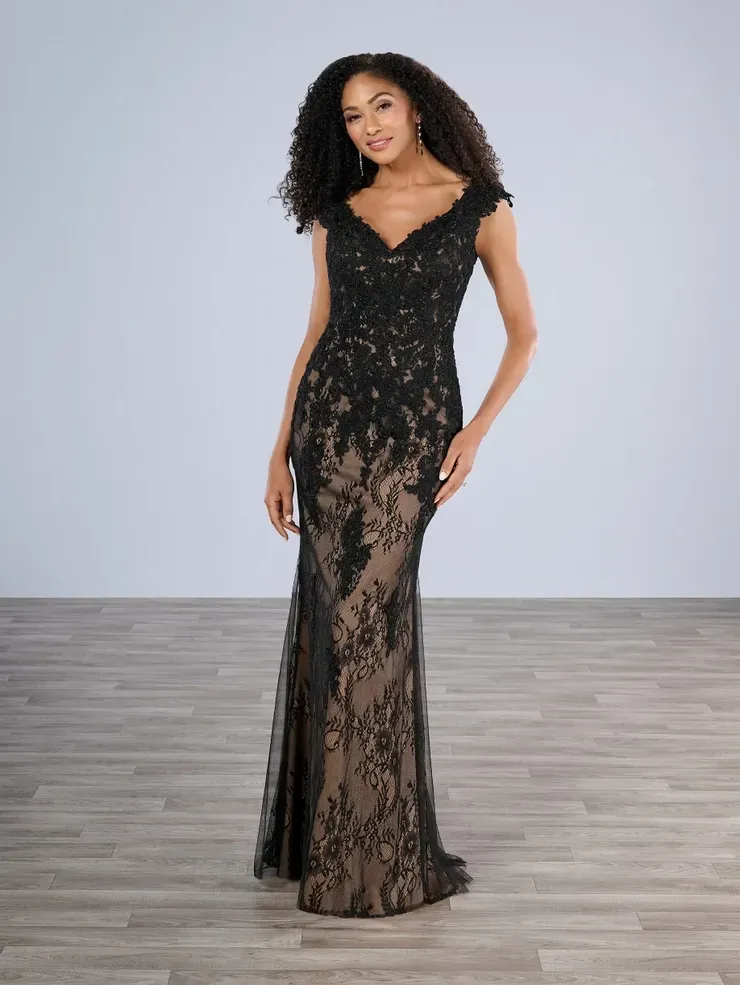 A woman in a black lace dress is standing on a wooden floor.