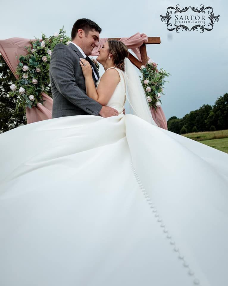 A bride and groom are kissing under a wooden arch.