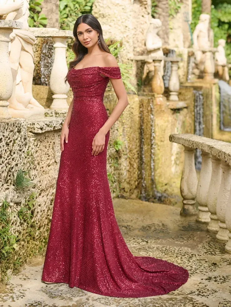 A woman in a long red dress is standing in front of a fountain.
