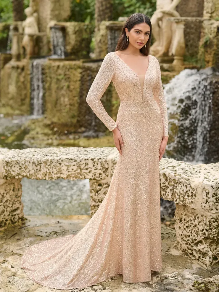 A woman in a long dress is standing in front of a waterfall.