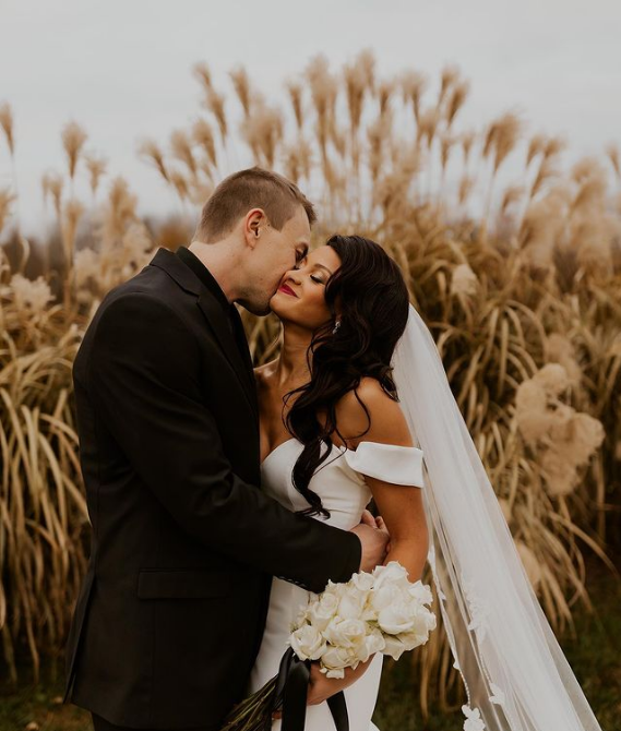 A bride and groom kissing in a field of tall grass