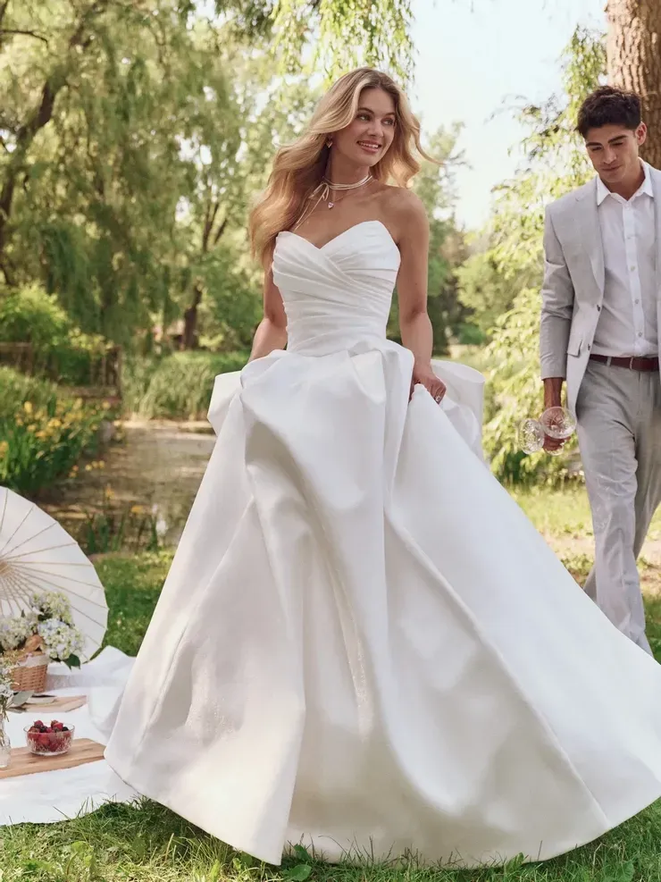 A woman in a white wedding dress is standing next to a man in a suit.