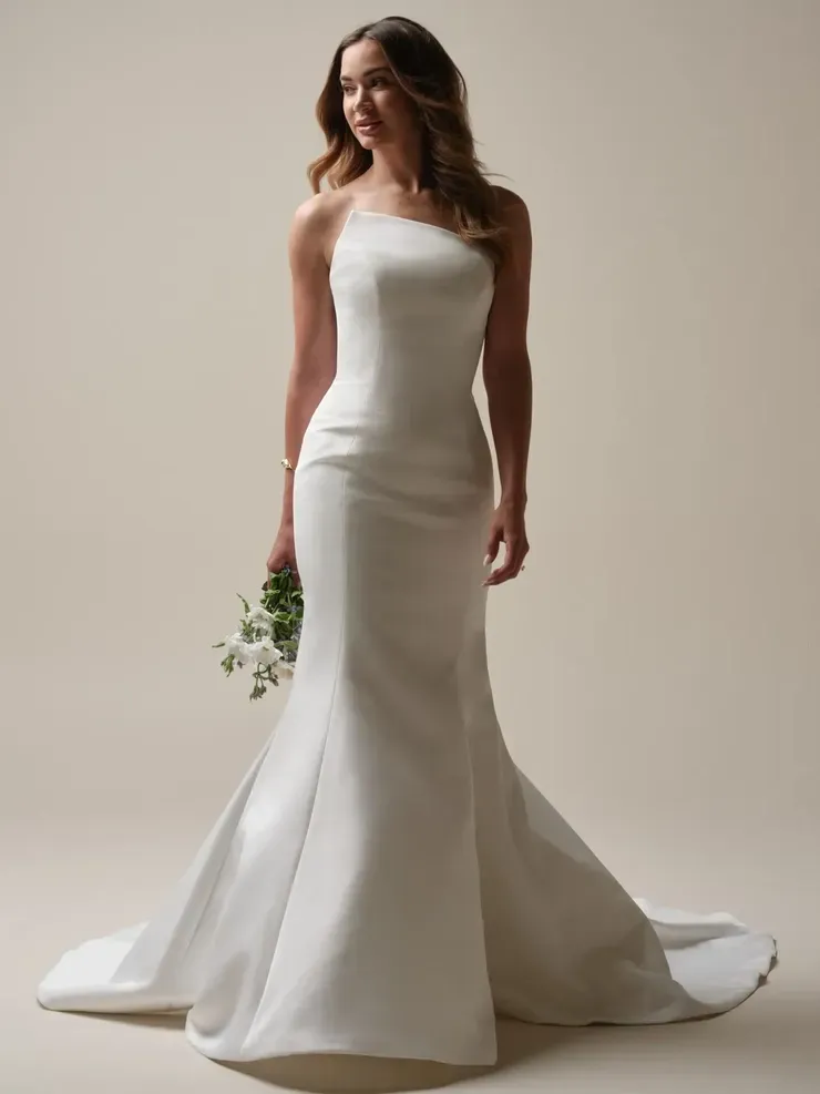 A woman in a white wedding dress is holding a bouquet of flowers.
