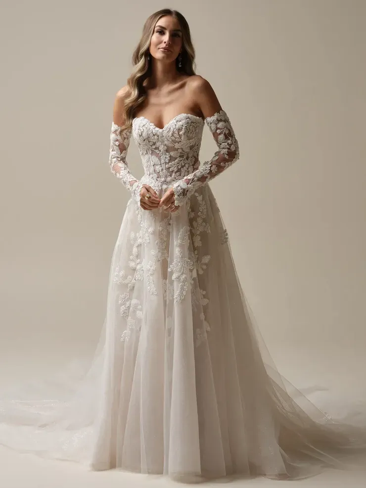 A woman is wearing a white wedding dress with long sleeves.