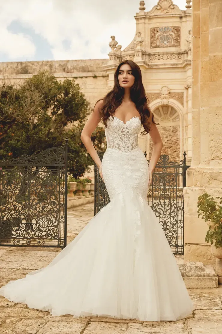 A woman in a white wedding dress is standing in front of a building.