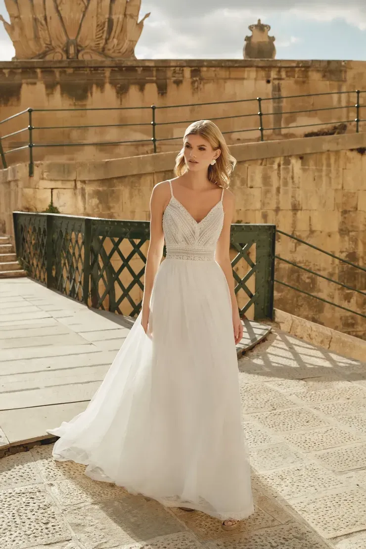 A woman in a white wedding dress is standing in front of a building.