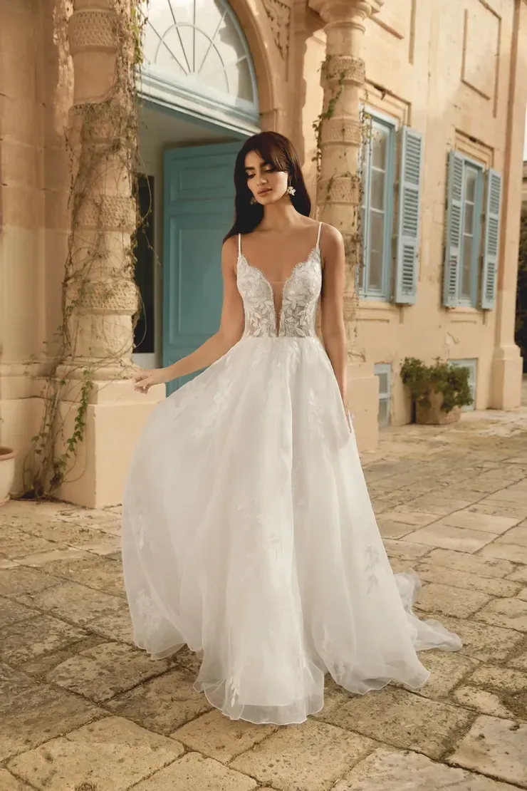 A woman in a white wedding dress is standing in front of a building.
