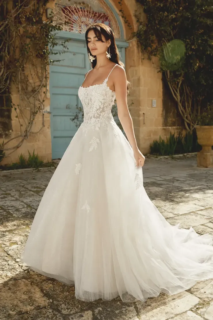 A woman in a white wedding dress is standing in front of a building.