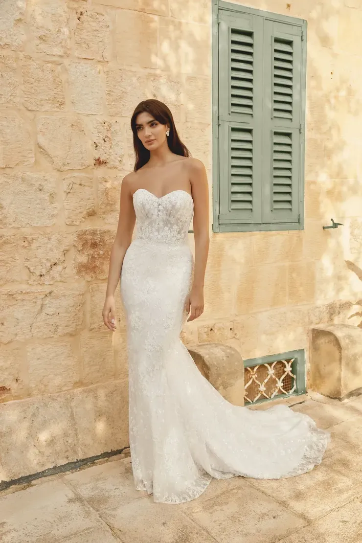 A woman in a white wedding dress is standing in front of a building.
