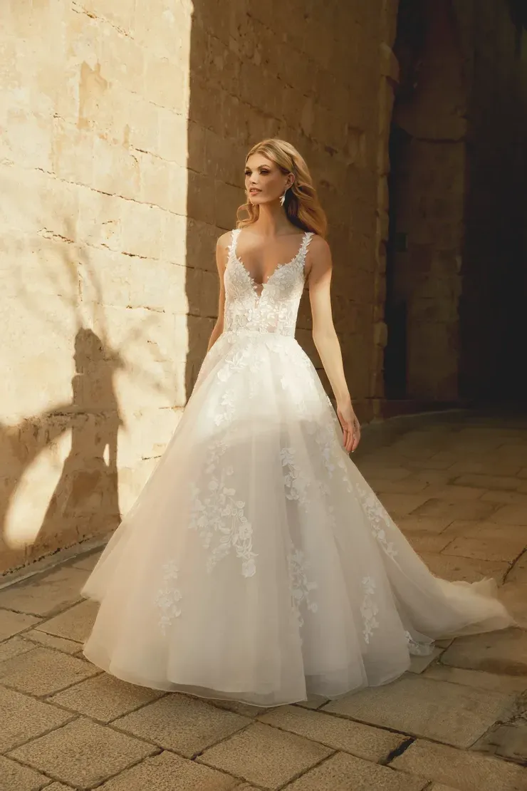 A woman in a white wedding dress is standing in front of a building.