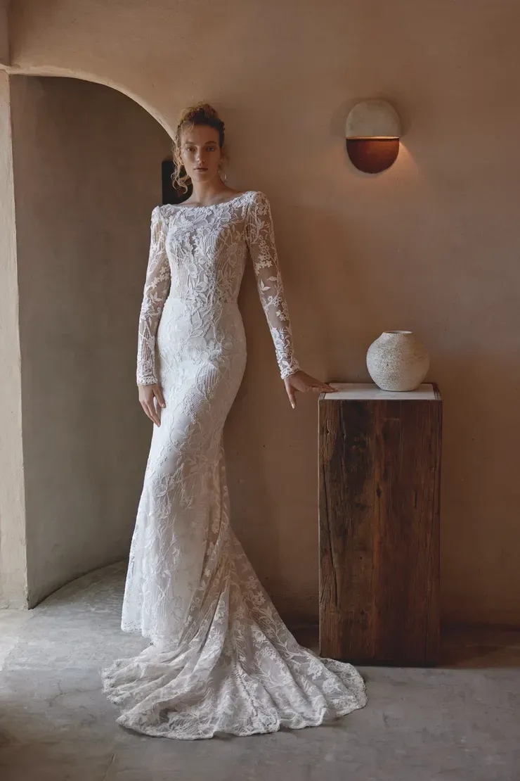 A woman in a wedding dress is standing next to a wooden pillar.