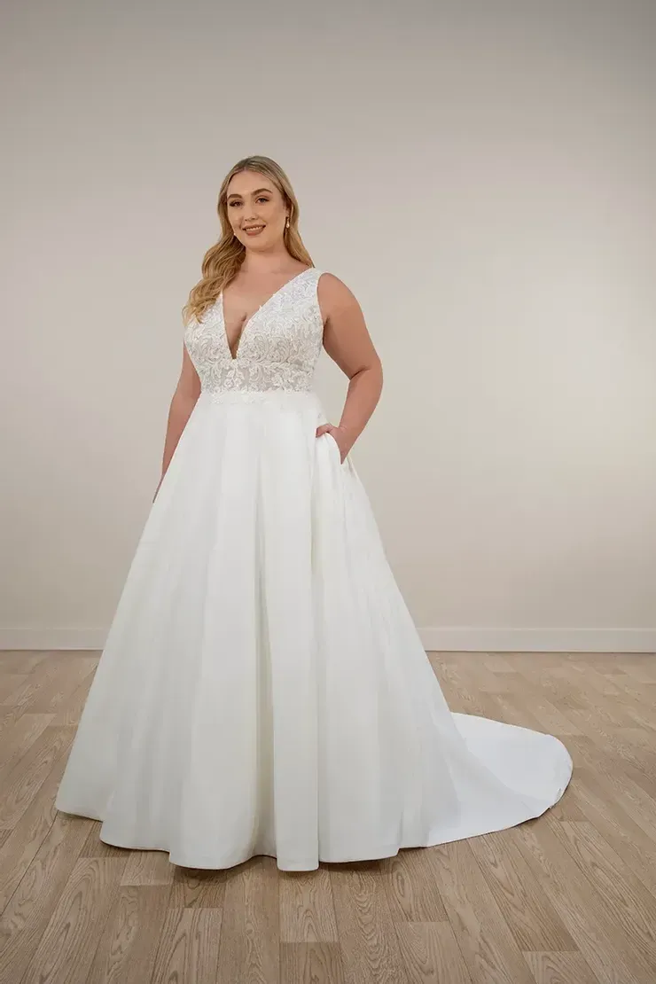 A plus size model is wearing a white wedding dress with pockets.