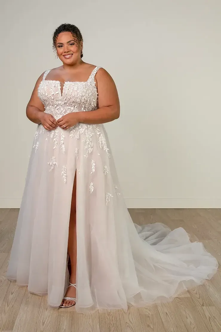 A plus size model is wearing a white wedding dress with a high slit.