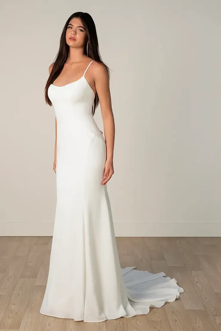 A woman in a white wedding dress is standing on a wooden floor.