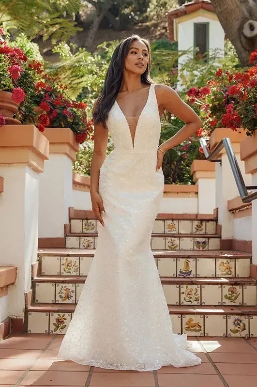 A woman in a white wedding dress is standing on a set of stairs.