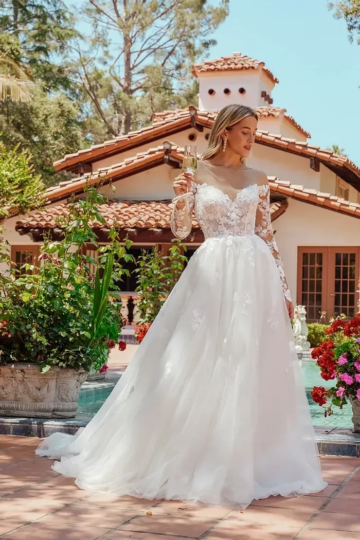 A woman in a white wedding dress is standing in front of a house.