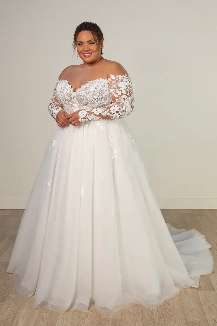 A plus size woman is wearing a white wedding dress with long sleeves.