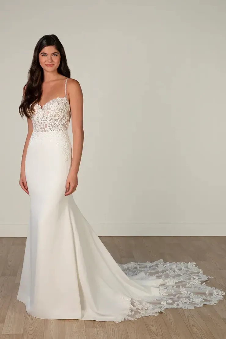 A woman in a white wedding dress is standing on a wooden floor.