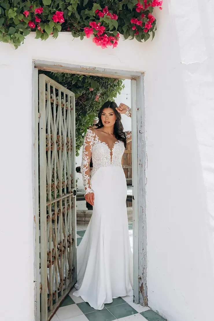 A woman in a white wedding dress is standing in a doorway.