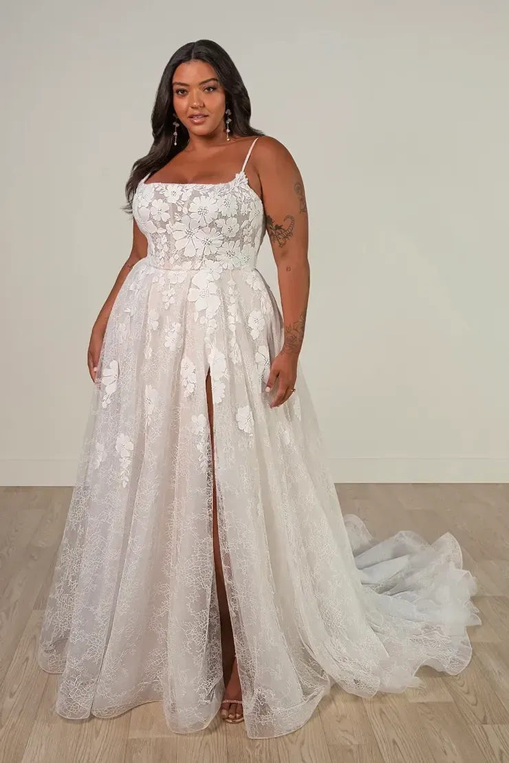A plus size model is wearing a white wedding dress with a high slit.