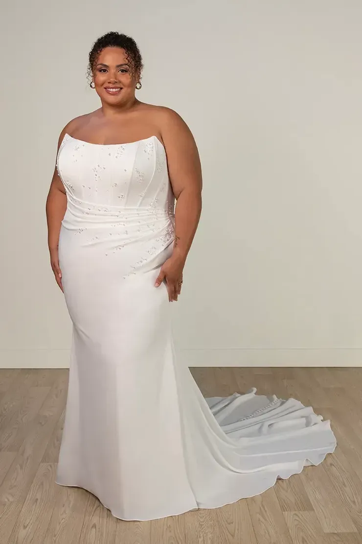 A plus size woman is wearing a white strapless wedding dress.