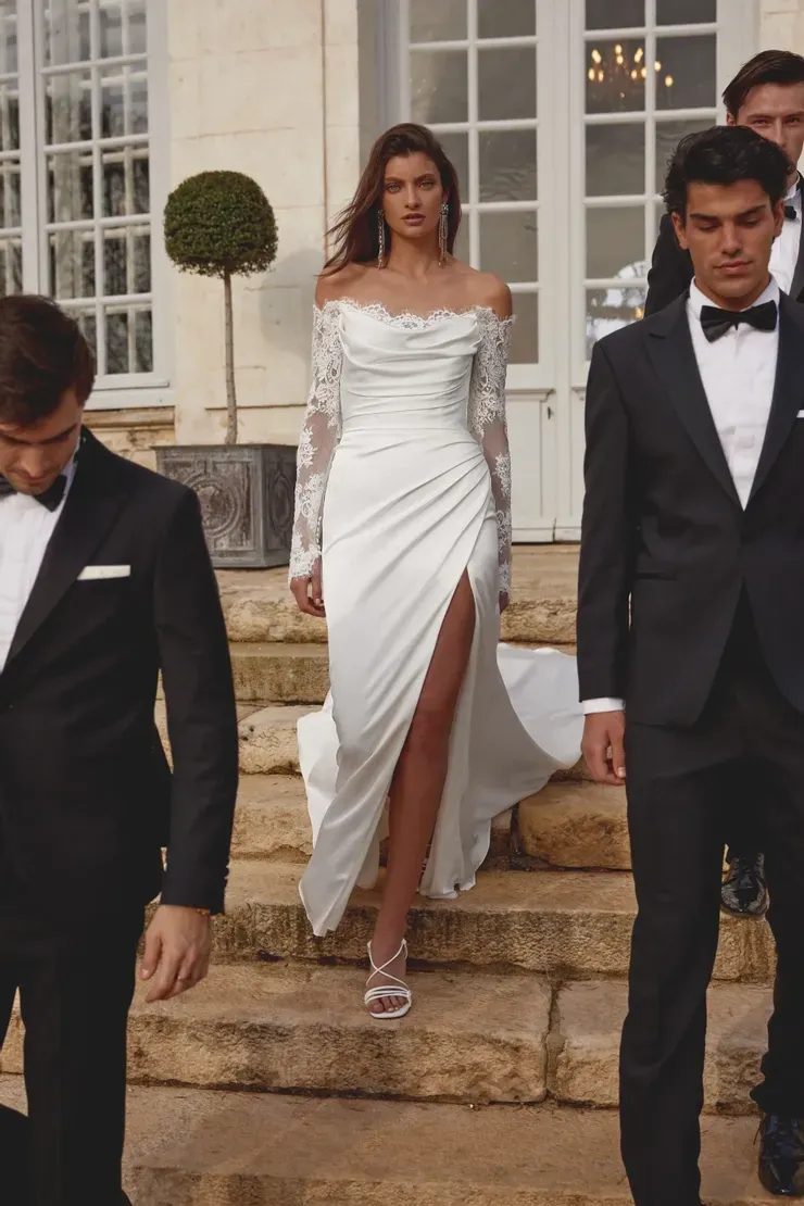 A woman in a white dress is walking down stairs with two men in tuxedos