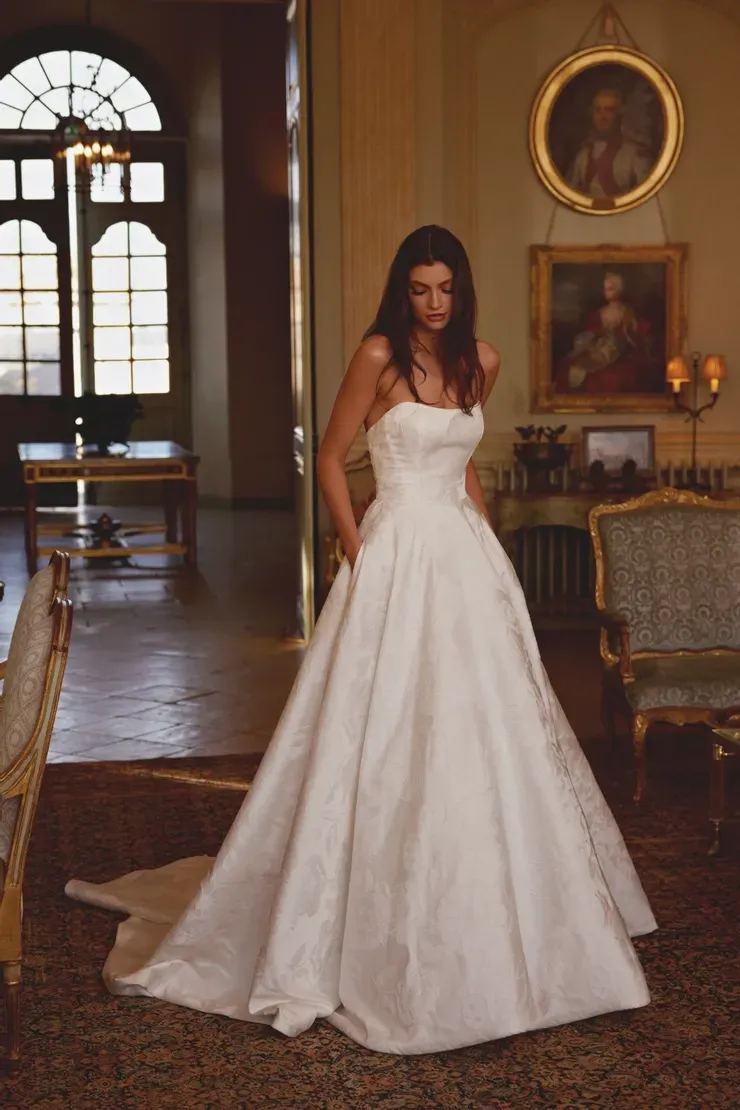 A woman in a white wedding dress is standing in a room.