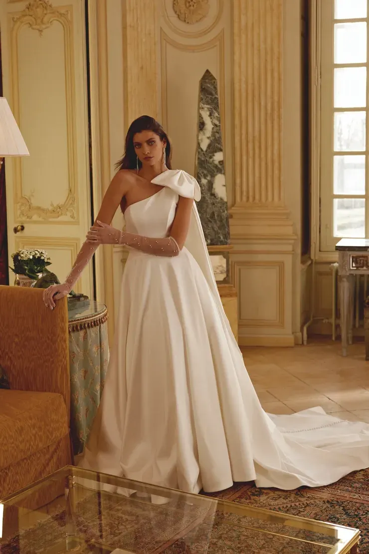 A woman in a white wedding dress is standing in a living room.