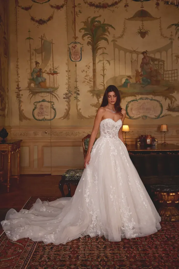 A woman in a white wedding dress is standing in a room.