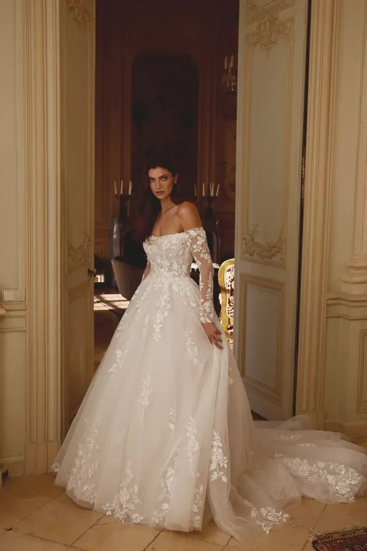 A woman in a wedding dress is standing in a doorway.