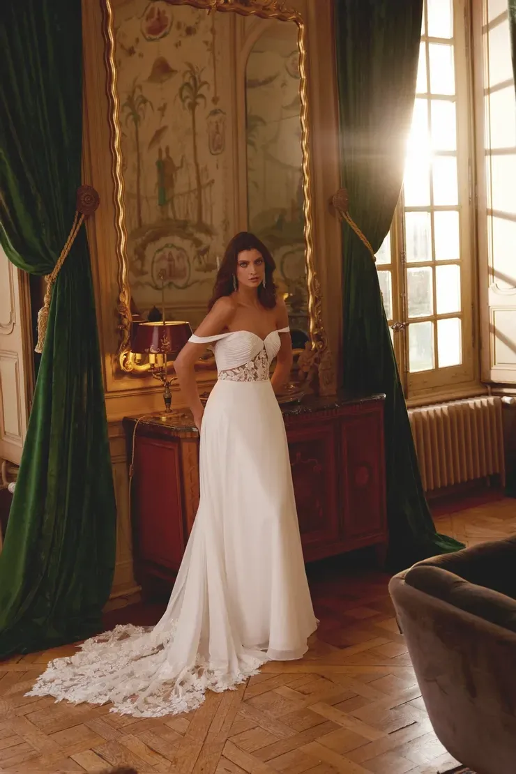 A woman in a wedding dress is standing in front of a mirror in a room.