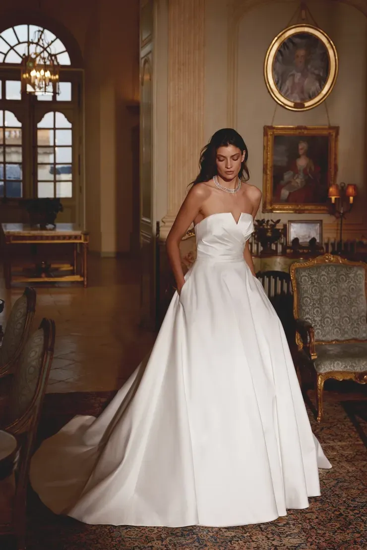 A woman in a white wedding dress is standing in a room.