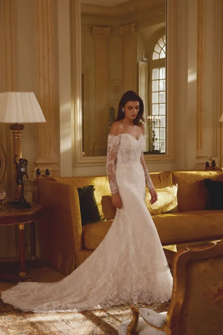 A woman in a wedding dress is standing in a living room next to a couch.