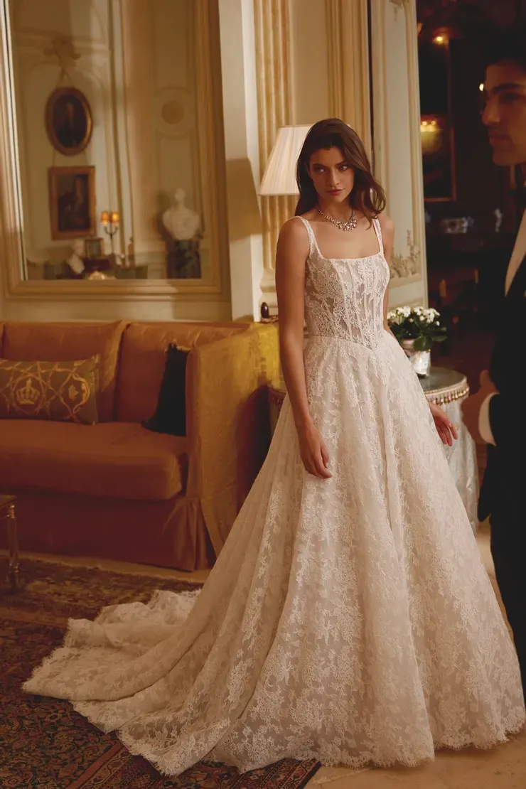 A woman in a wedding dress is standing next to a man in a tuxedo in a living room.