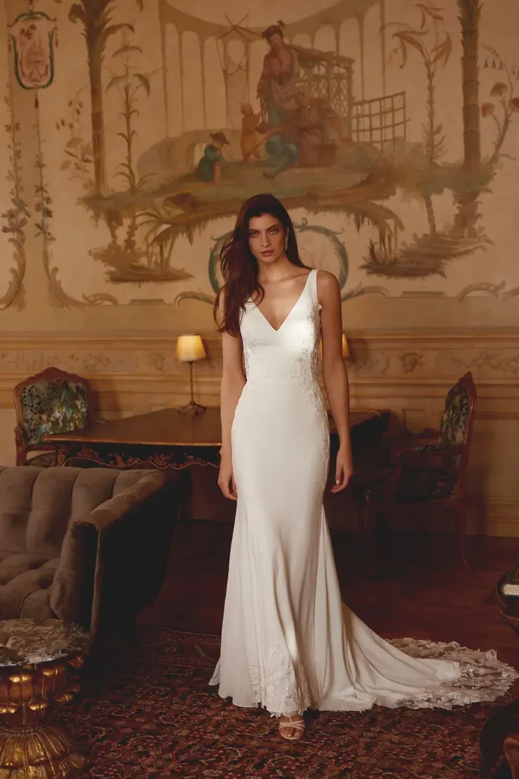 A woman in a white wedding dress is standing in a room.
