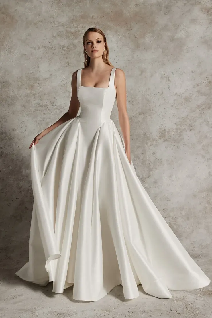 A woman is wearing a white wedding dress with a square neckline.